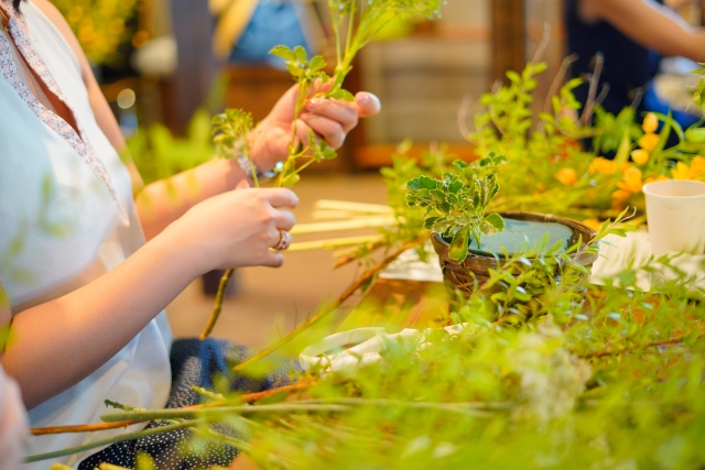 お花教室の体験レッスンで材料を持って座る女性のイメージ画像