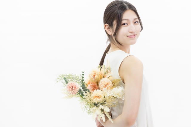 お花を持って笑顔になっている女性の画像