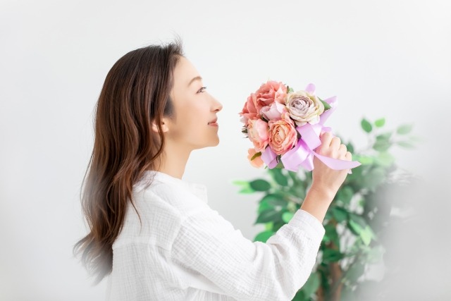 作成したフラワーアレンジメントを手に持つ女性